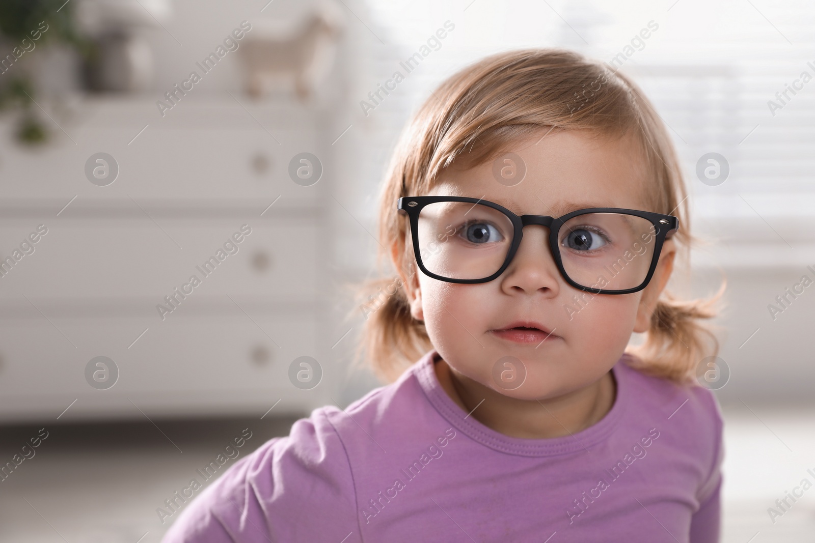 Photo of Cute little girl in glasses at home. Space for text