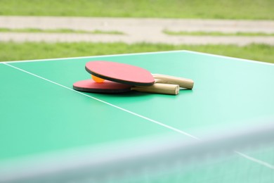 Photo of Tennis rackets and ball on ping pong table in park