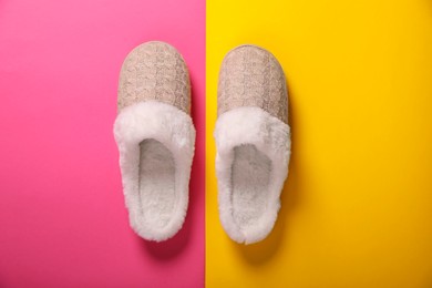 Pair of beautiful soft slippers on colorful background, top view