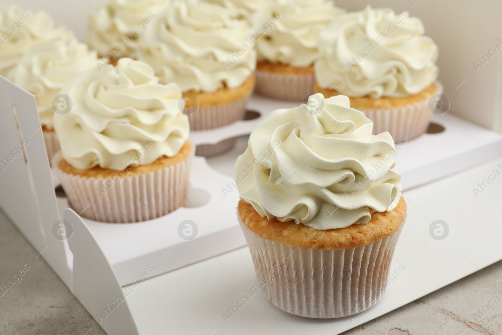 Photo of Tasty cupcakes with vanilla cream in box, closeup