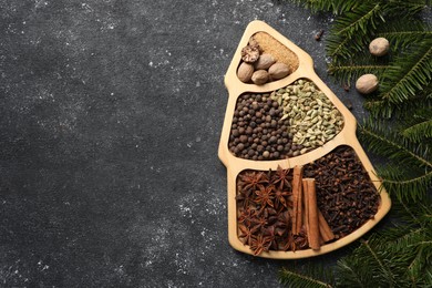 Photo of Different spices, nuts and fir branches on dark gray textured table, flat lay. Space for text