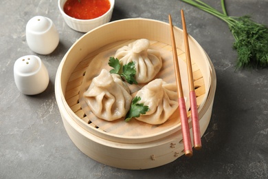 Photo of Bamboo steamer with tasty baozi dumplings and chopsticks on table