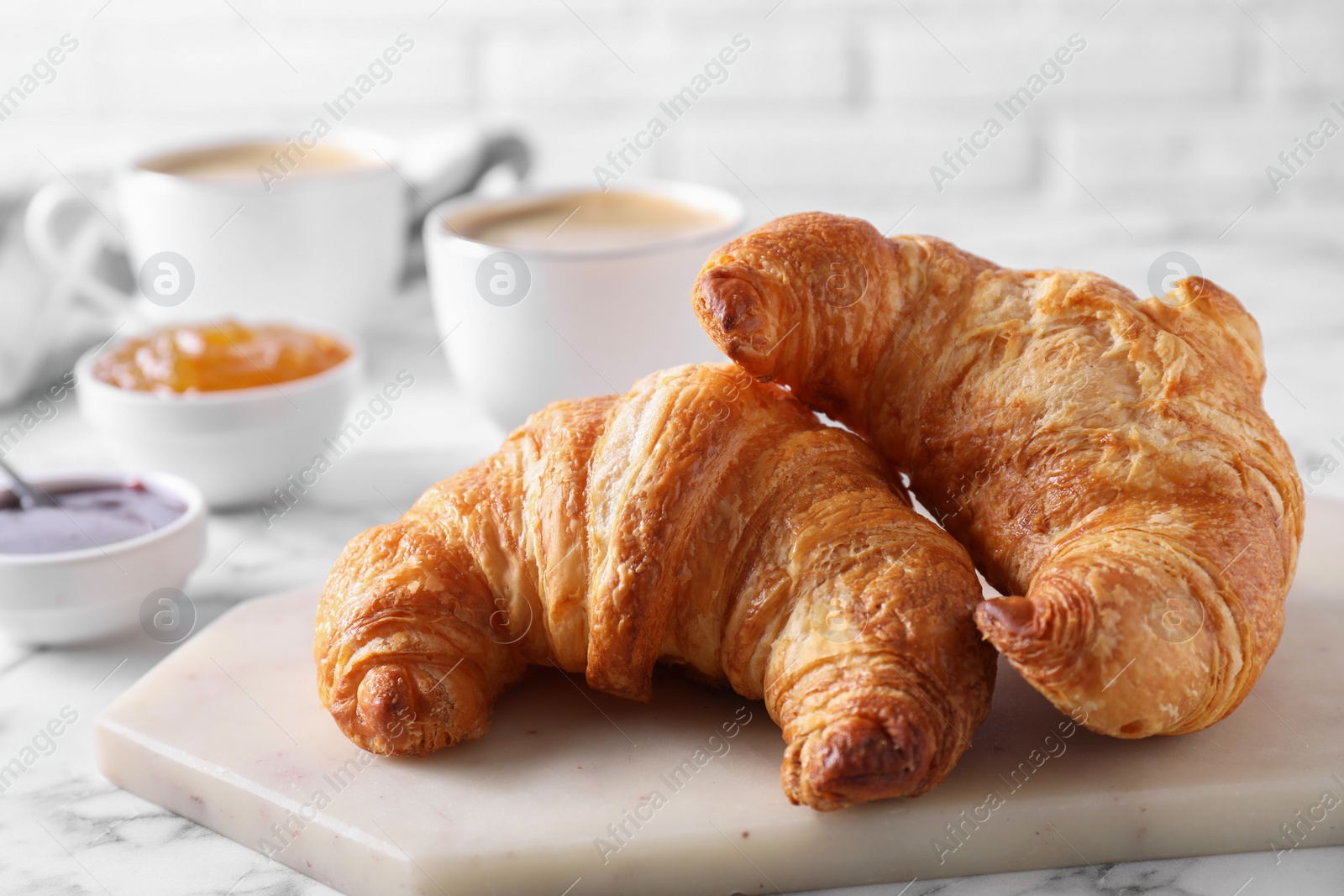 Photo of Tasty breakfast. Fresh croissants and jam on white marble table