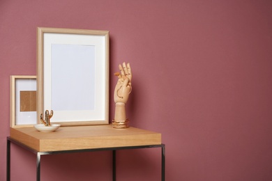 Photo of Mockup of blank frame and wooden hand on table