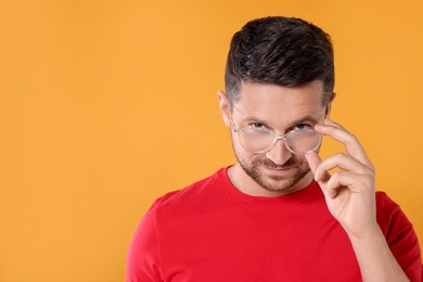 Portrait of man in stylish glasses on yellow background. Space for text