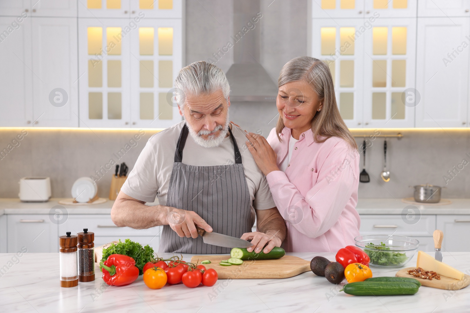 Photo of Affectionate senior couple cooking together in kitchen