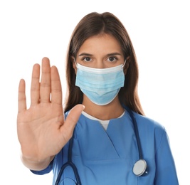 Doctor in protective mask showing stop gesture on white background. Prevent spreading of coronavirus