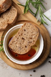 Bowl of organic balsamic vinegar with oil served with spices and bread slices on beige table, flat lay