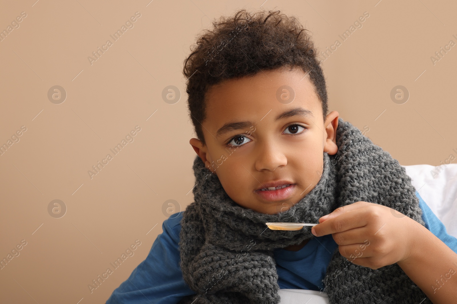 Photo of African-American boy taking cough syrup on bed at home, space for text. Cold medicine