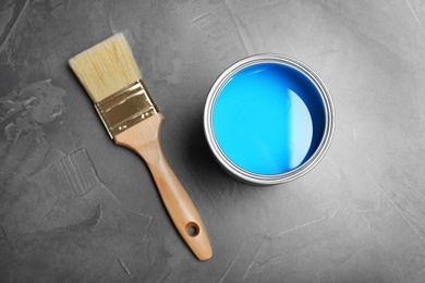 Photo of Can with blue paint and brush on gray background, top view