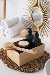 Photo of Wooden box with different toiletries and brush on countertop in bathroom