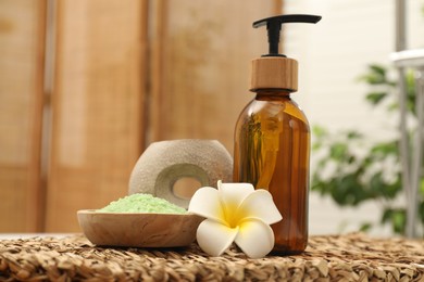 Photo of Different spa products and beautiful flower on wicker table, closeup