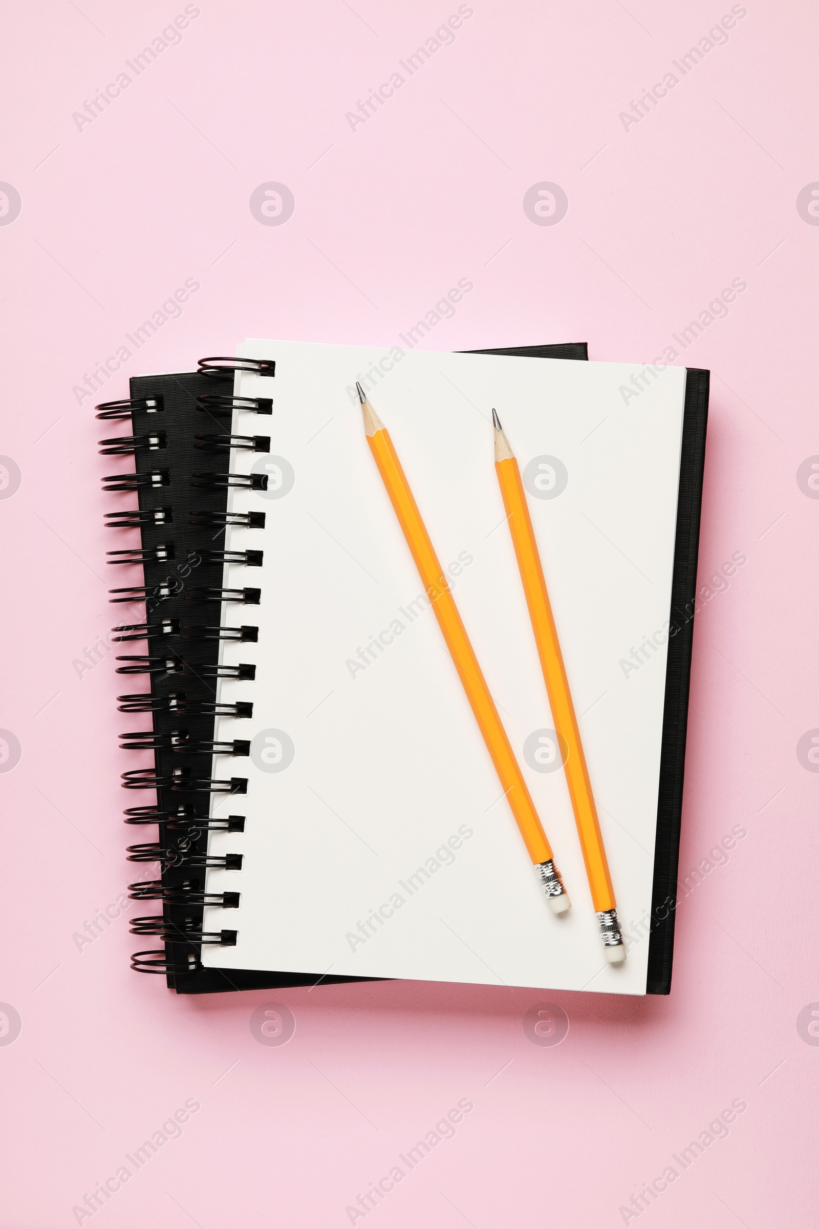 Photo of Notebooks and pencils on pale pink background, top view