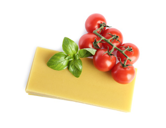 Uncooked lasagna sheets, tomatoes and basil on white background, top view