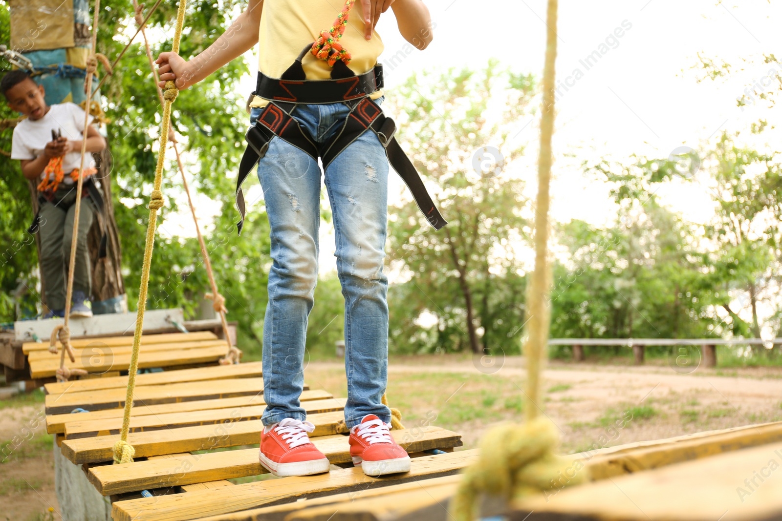 Photo of Little girl climbing in adventure park, closeup. Summer camp