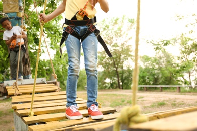 Photo of Little girl climbing in adventure park, closeup. Summer camp