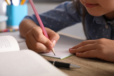 Photo of Preteen girl doing homework at table, closeup