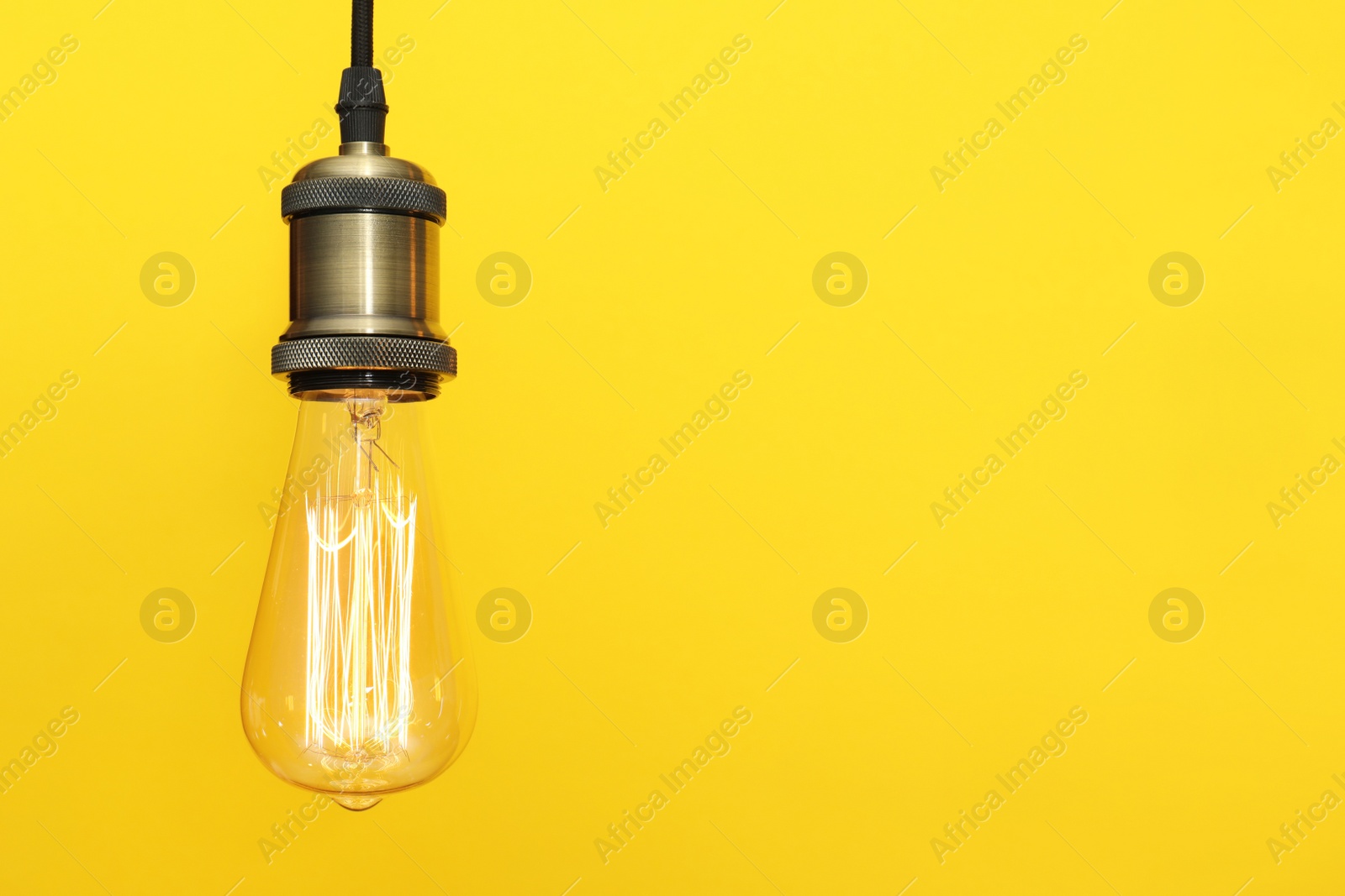 Photo of Pendant lamp with light bulb on color background, space for text