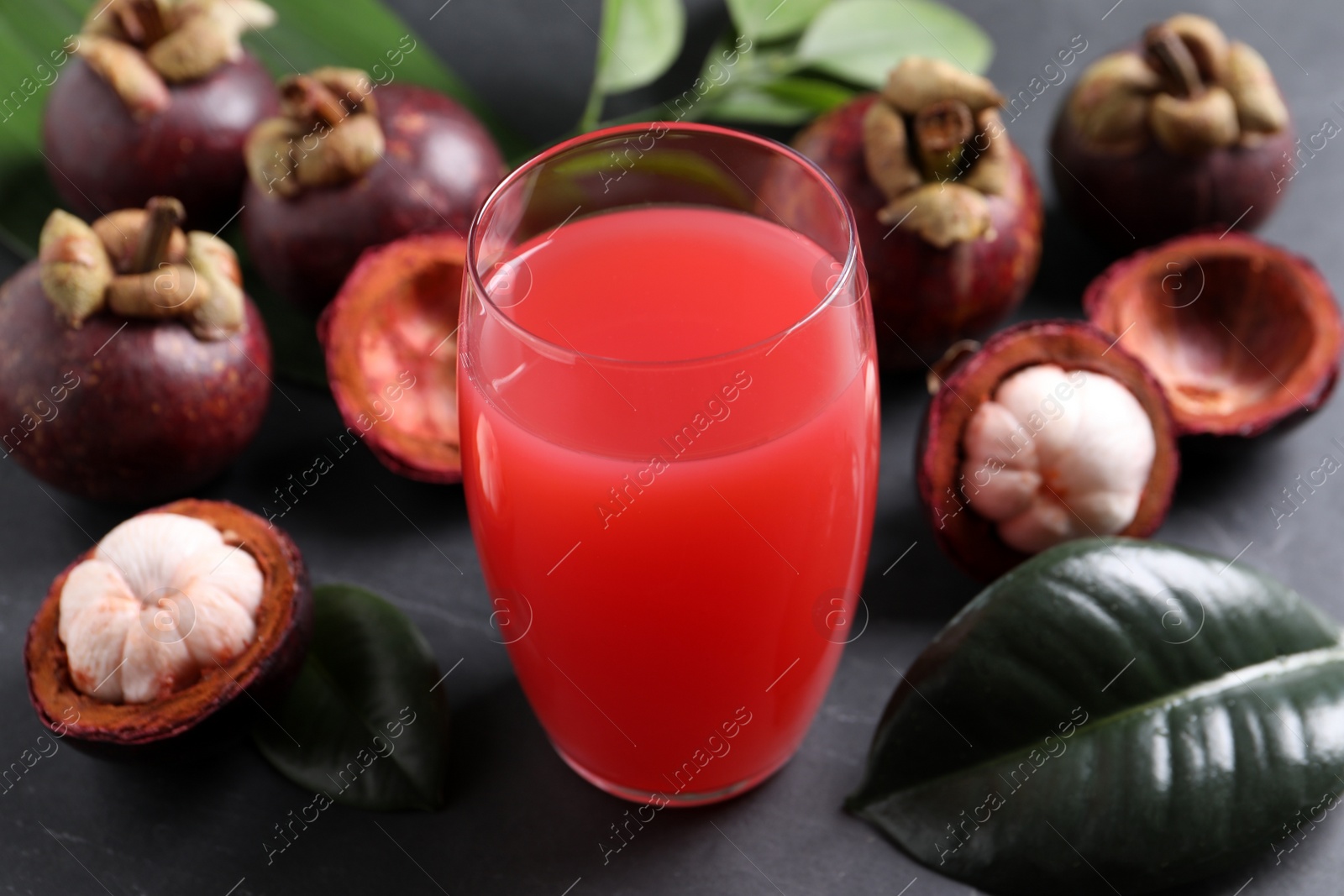 Photo of Delicious mangosteen juice in glass on dark table