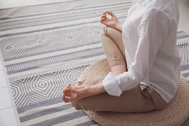 Woman meditating on wicker mat at home, closeup. Space for text