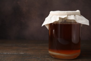 Tasty kombucha in glass jar on wooden table, space for text