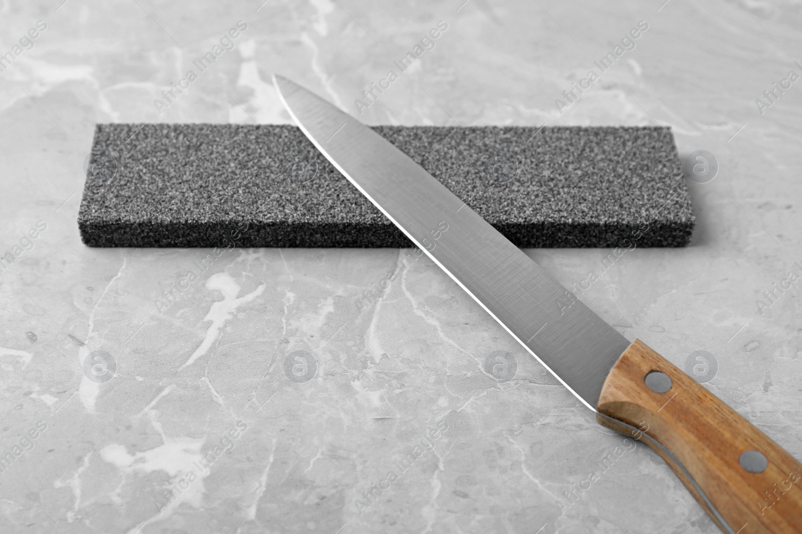 Photo of Knife and sharpening stone on grey background