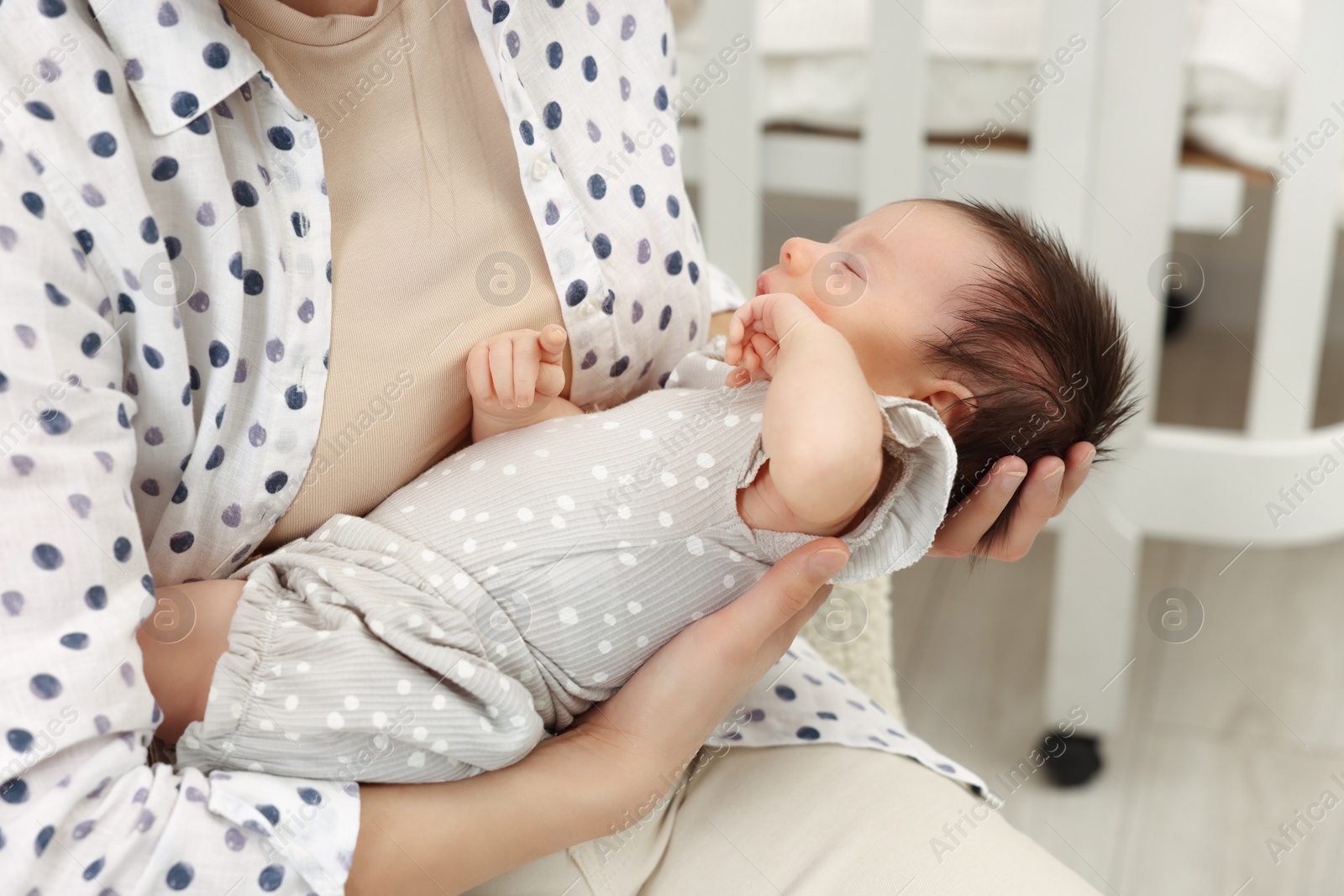 Photo of Mother with her sleeping newborn baby indoors, closeup