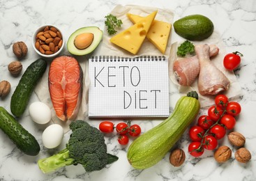 Photo of Notebook with words Keto Diet and fresh products on white marble table, flat lay