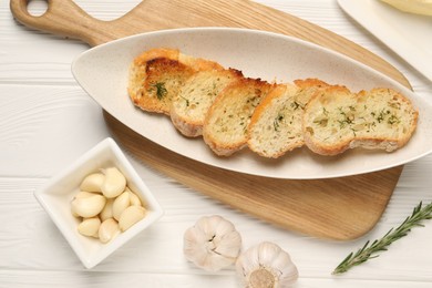 Tasty baguette with garlic, dill and rosemary on white wooden table, flat lay