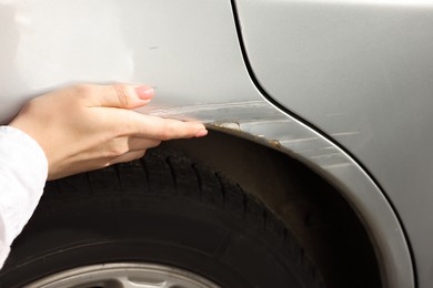 Photo of Woman near car with scratch, closeup view