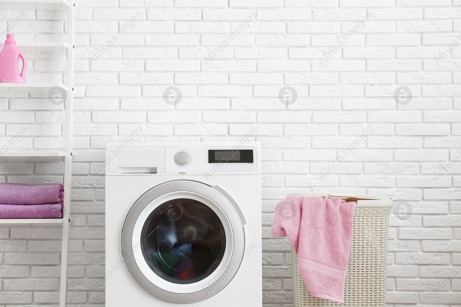 Photo of Modern washing machine near brick wall in laundry room interior