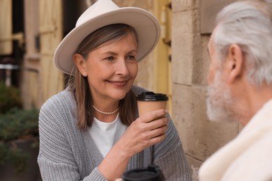 Photo of Affectionate senior couple sitting in outdoor cafe and drinking coffee