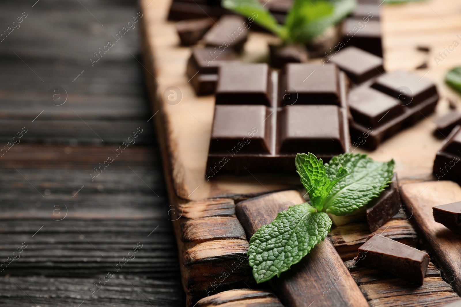 Photo of Pieces of dark chocolate with mint on wooden table