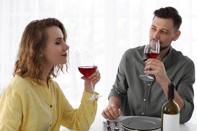 Young couple with glasses of wine at table in restaurant