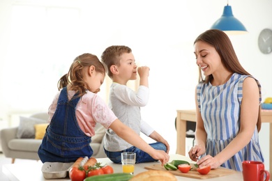 Young woman cooking breakfast for her children in kitchen. Happy family