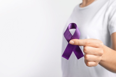 Woman holding purple ribbon on white background, closeup with space for text. Domestic violence awareness