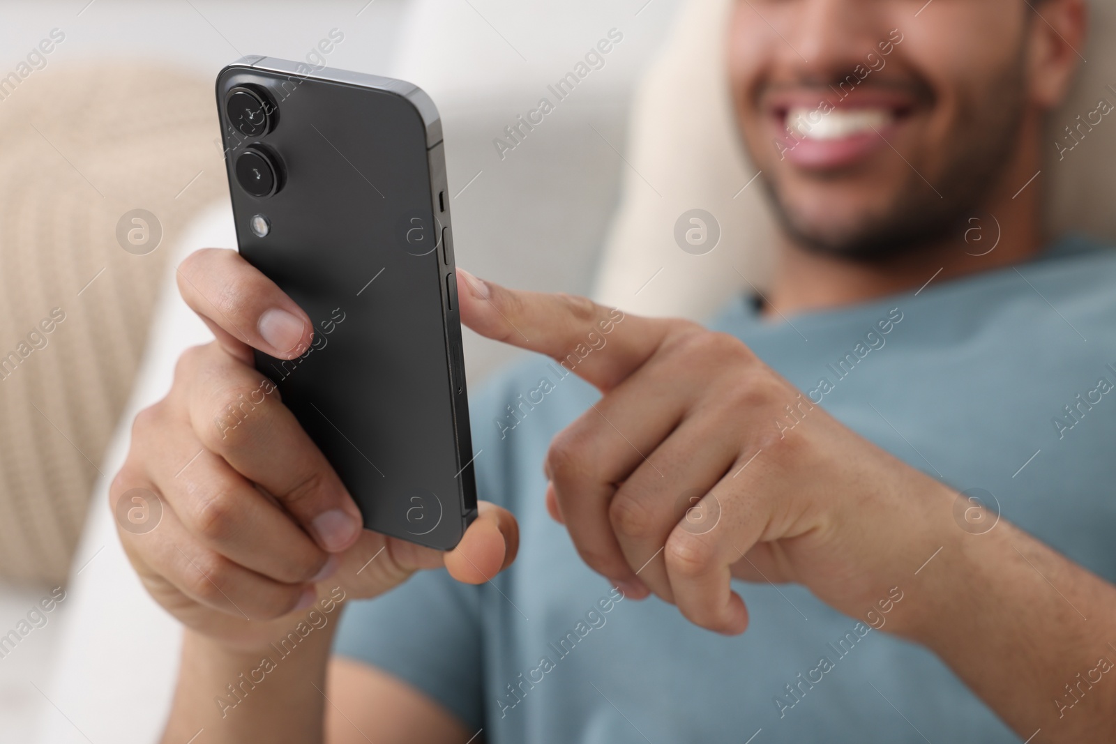 Photo of Man sending message via smartphone indoors, selective focus