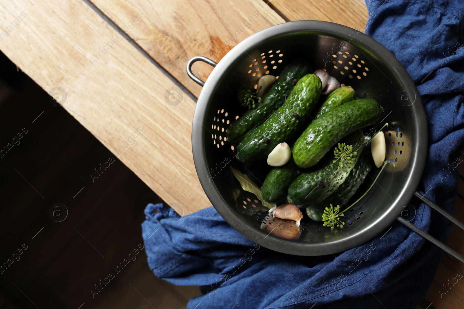 Photo of Fresh cucumbers and other ingredients prepared for canning on wooden table, top view. Space for text