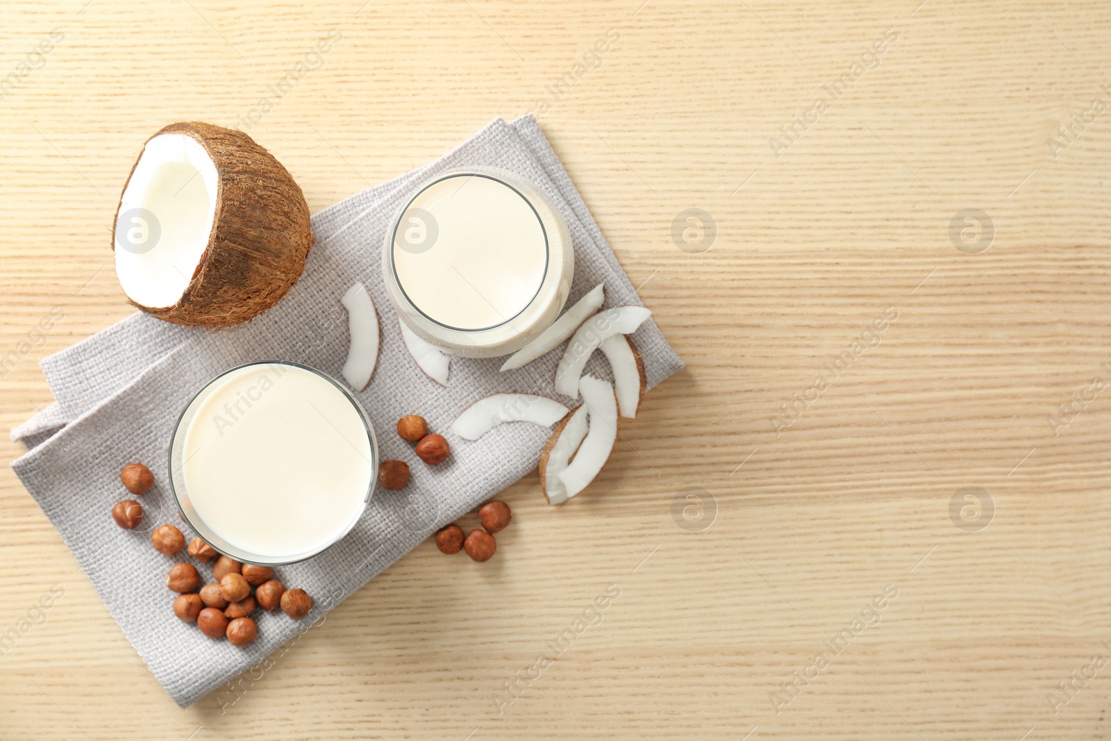 Photo of Glasses with milk substitute and nuts on wooden background, flat lay