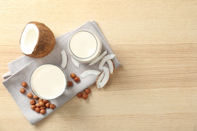 Photo of Glasses with milk substitute and nuts on wooden background, flat lay