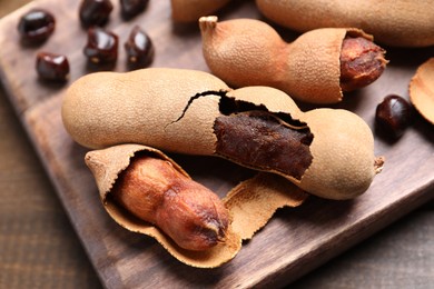 Photo of Delicious ripe tamarinds on wooden board, closeup