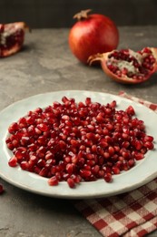 Photo of Tasty ripe pomegranate grains on grey table