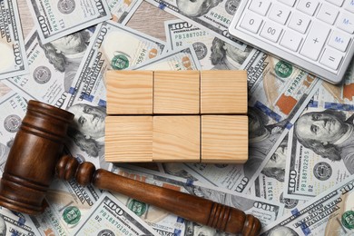 Photo of Tax law. Blank wooden cubes, dollar banknotes, gavel and calculator on table, top view