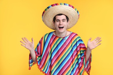 Photo of Excited man in Mexican sombrero hat and poncho on yellow background