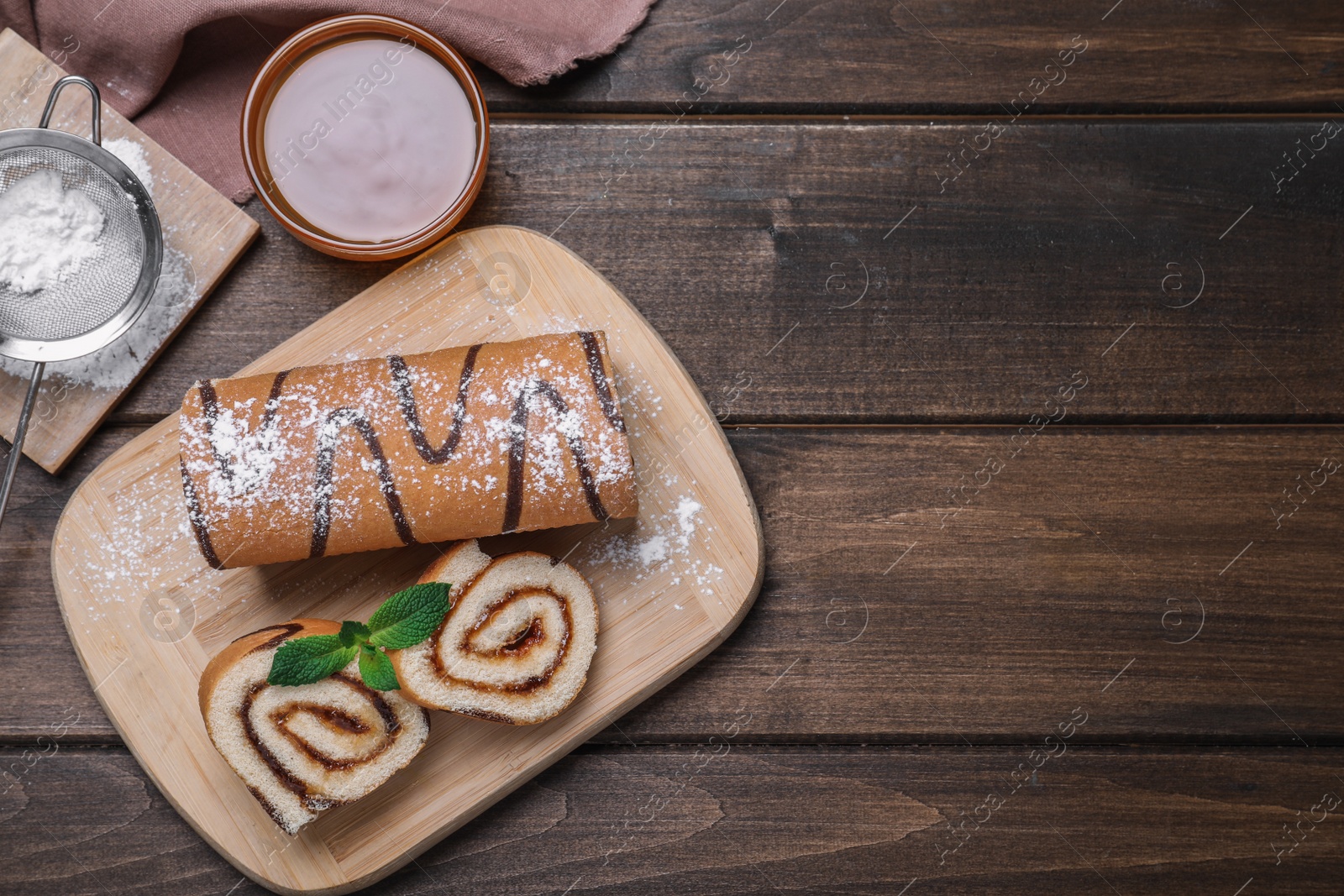 Photo of Tasty cake roll with jam on wooden table, flat lay. Space for text