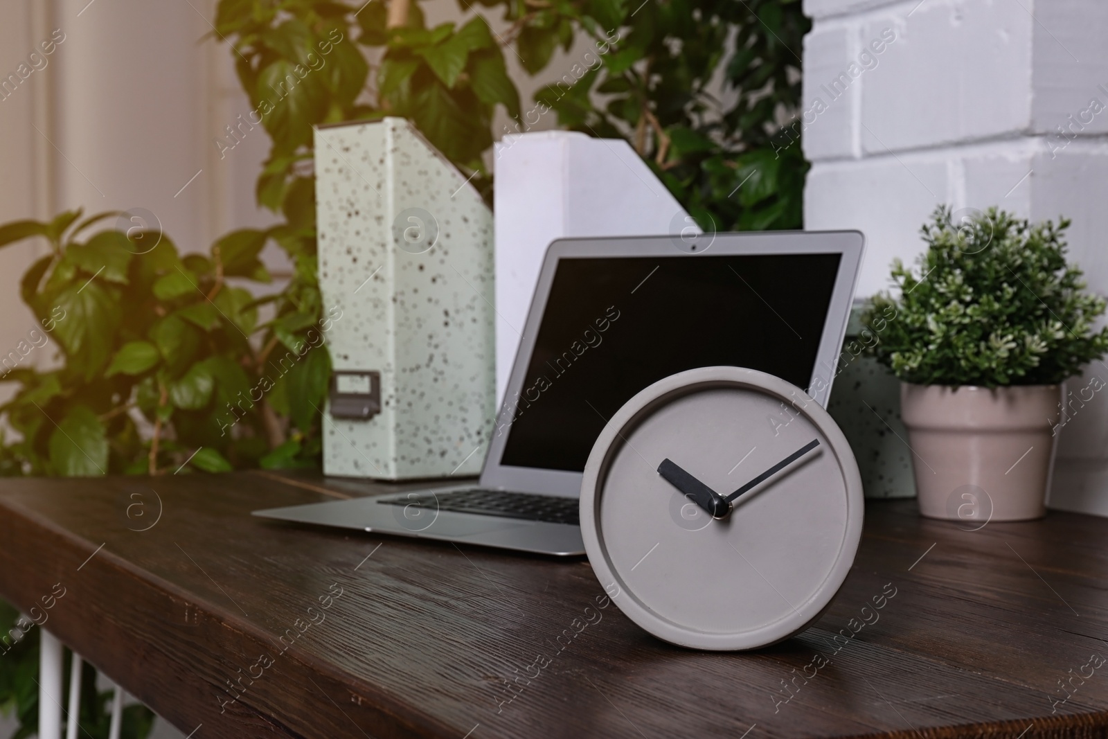 Photo of Workplace with stylish analog clock and laptop in office. Space for text