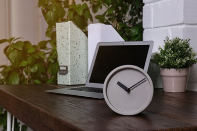 Workplace with stylish analog clock and laptop in office. Space for text