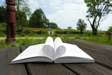 Open book on wooden table in countryside
