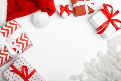 Santa Claus red hat, gift boxes and beard on white background, top view