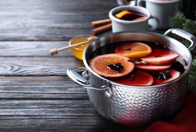 Delicious mulled wine and ingredients on black wooden table. Space for text